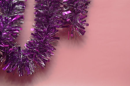 Purple tinsel on a pink background. Christmas and New Year background.