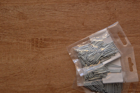 Nails in a plastic bag on a wooden background, top viewの写真素材