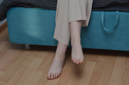 Close up of woman legs sitting on bed at home. Female legs in bed.