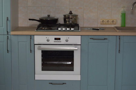 Kitchen interior with modern electric stove and gas stove in blue.
