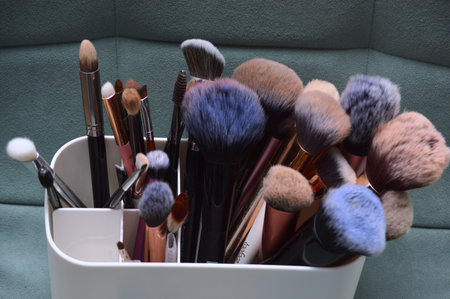 Makeup brushes in a white vase on a green background.の写真素材