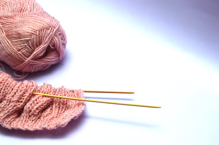 Knitting needles and pink wool yarn on white background, closeup