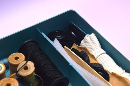 Sewing accessories in a box on a lilac background.