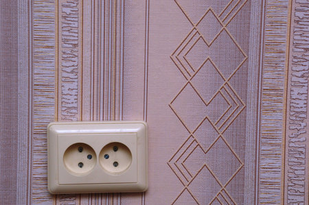 Electrical socket on the background of a wall with a pattern.