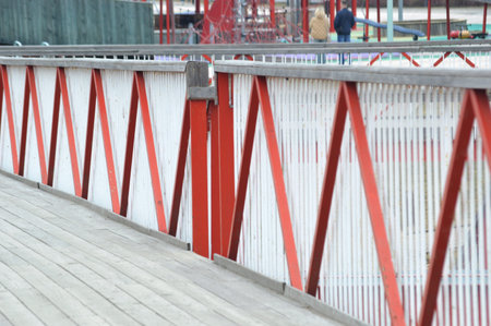 red and white metal fence on the bridge over the river in the city