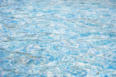 Blue water surface in swimming pool with sun reflections. Abstract background.