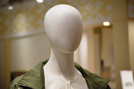 Mannequin wearing a green jacket in a fashion store window.