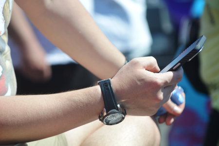 Close-up of a man using a smartwatch and mobile phoneの写真素材