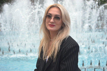 Portrait of a beautiful young woman in sunglasses against the background of a fountainの写真素材