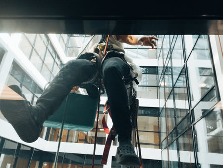 Low angle view of man and woman hanging on rope in office buildingの写真素材