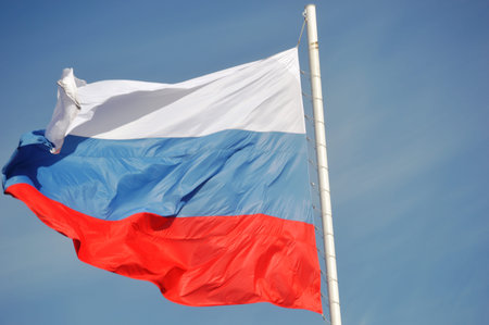 Flag of Russia waving in the wind on a blue sky background.