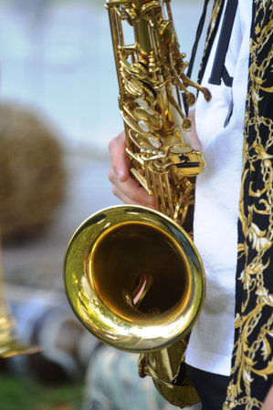 Saxophone in the hands of a musician, closeup of photoの写真素材