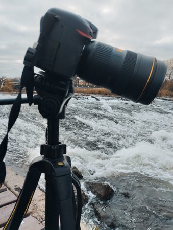 Professional camera on tripod on the background of the river and cloudy sky