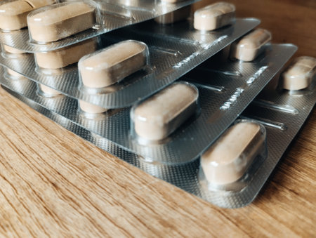 Tablets in blister packs on wooden background. Focus on foreground, soft bokeh.の写真素材