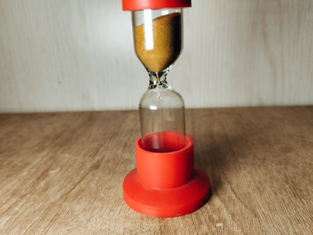 Hourglass on wooden background. Sand running through the glass. Time passing conceptの写真素材