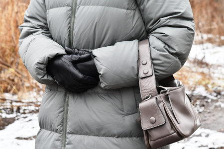 A person in a winter jacket holds a bag in their hands.の写真素材