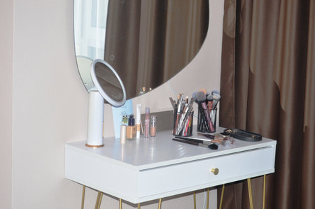 Makeup products and mirror on dressing table in dressing room at homeの写真素材