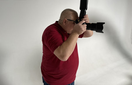 Photographer in red t-shirt with a professional camera on his shoulder