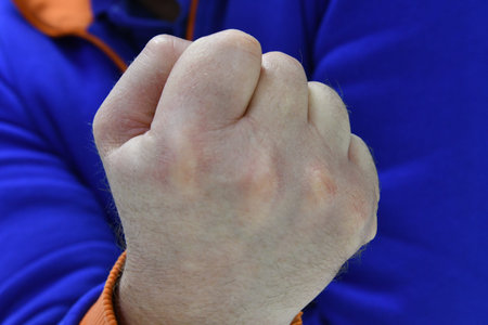 Close up of a man's fist in a blue sports jacket.