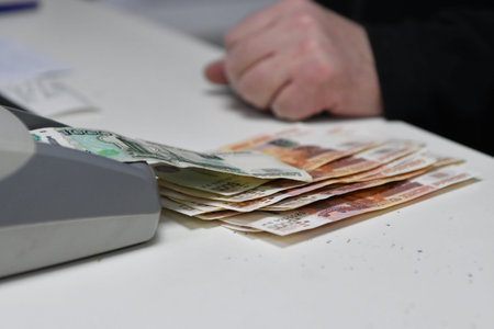 Cashier counting banknotes at the cash register in the office
