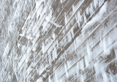 White brick wall covered with snow in winter. Abstract background for design.