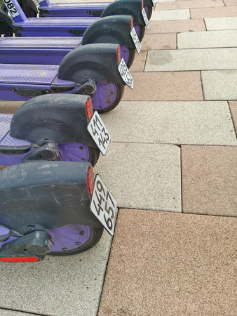 Electric scooters parked in a row on the pavement of a streetの写真素材