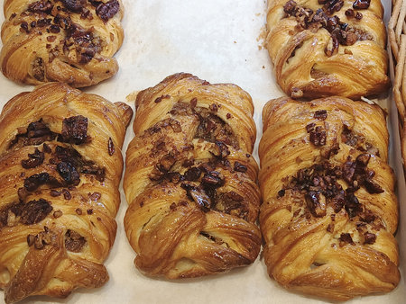Freshly baked pastries with raisins and nuts on a baking sheetの写真素材