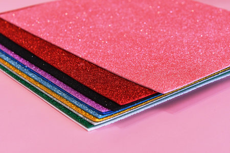 Close-up of a pile of multicolored papers on pink background