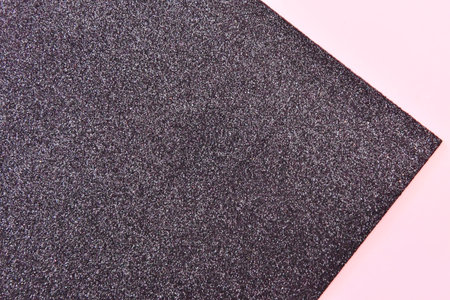 Black foam rubber sponge on pink background, top view, copy space