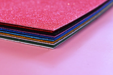 close up of a stack of colorful sheets of paper on pink background