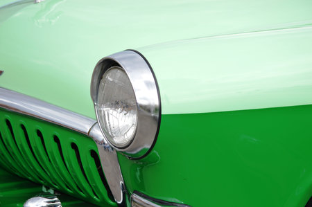 A close up of the headlight and radiator grille of a vintage green car in Gloucester, Virginia.