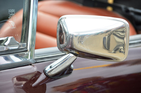 Detail of a classic car's front side mirror and hood.