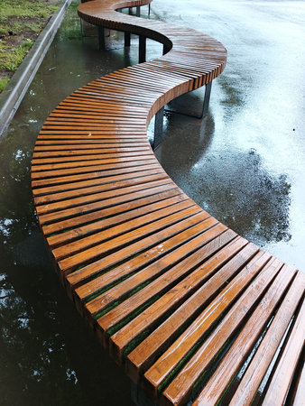 Wooden bench in the park on a rainy day. Nobody.