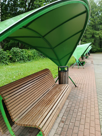Public park bench in the city park with green benches and trees.の写真素材