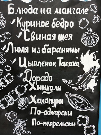 Blackboard with a menu of pizza, mushrooms, olives and salamiの写真素材