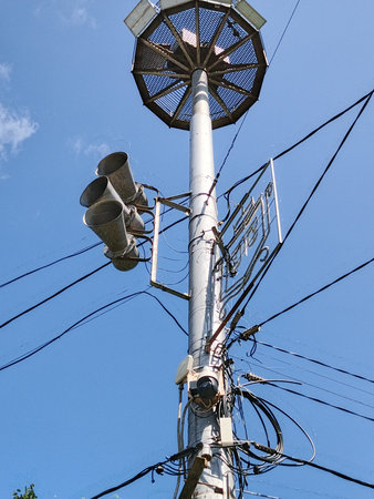 Loudspeakers on a street light pole with blue sky background