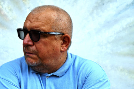 An old man in a blue polo shirt and black sunglasses.