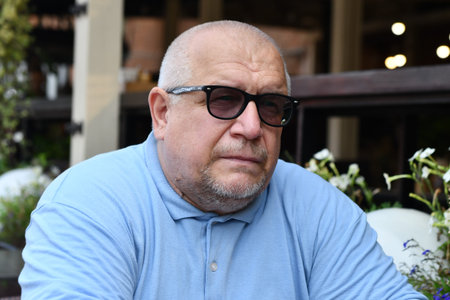 Portrait of a senior man with glasses sitting in a cafe.