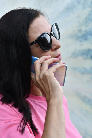 Portrait of a woman in sunglasses with a mobile phone in her hand
