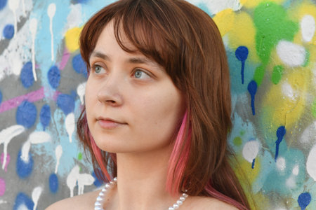 Portrait of a beautiful girl with pink hair on the background of graffiti wallの写真素材