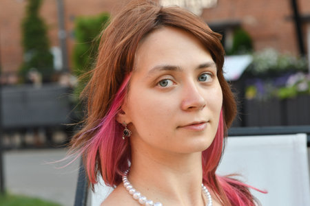 Portrait of a young woman with pink hair on the street.