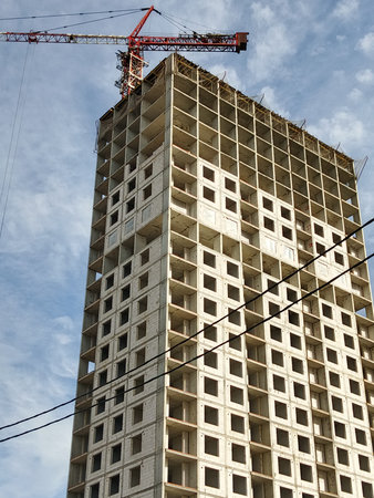 Construction of a multi-storey building with a crane on a background of blue sky