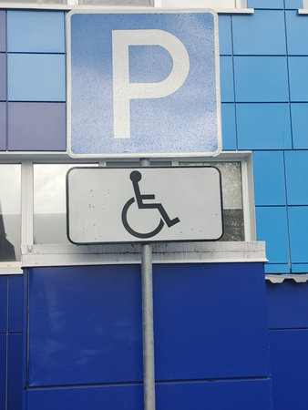 Parking sign in front of a blue wall with a wheelchair.の写真素材