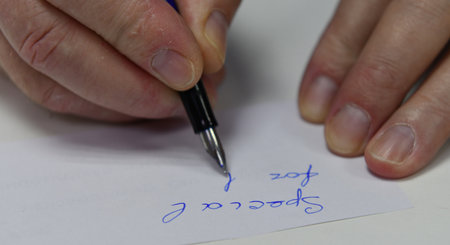 Close-up of a man's hand writing on a piece of paper with a penの写真素材