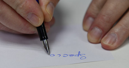 Man's hand writing on a piece of paper with a pen.