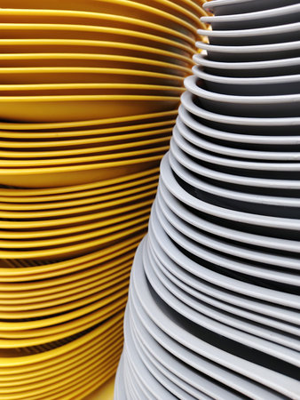 Close up of stack of white and yellow paper plates on yellow background