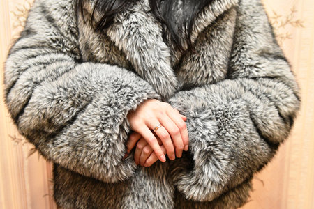Womans hands in fur coat on wooden background, closeupの写真素材