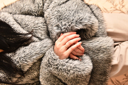 Female hands in fur coat on sofa, closeup. Winter fashionの写真素材