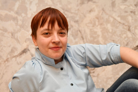 portrait of a red-haired girl in a blue shirt on a gray background