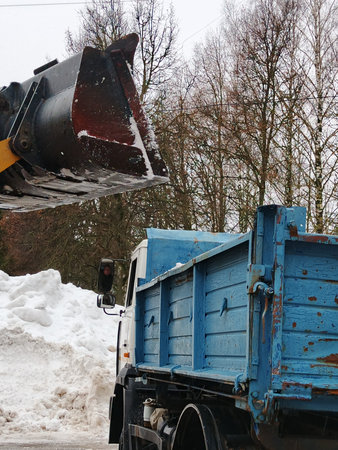 Snow removal machine removes snow from the road with a bucket of snow